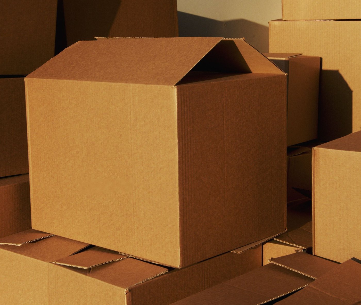 Plain brown corrugated boxes stacked in warm light, one open at the front
