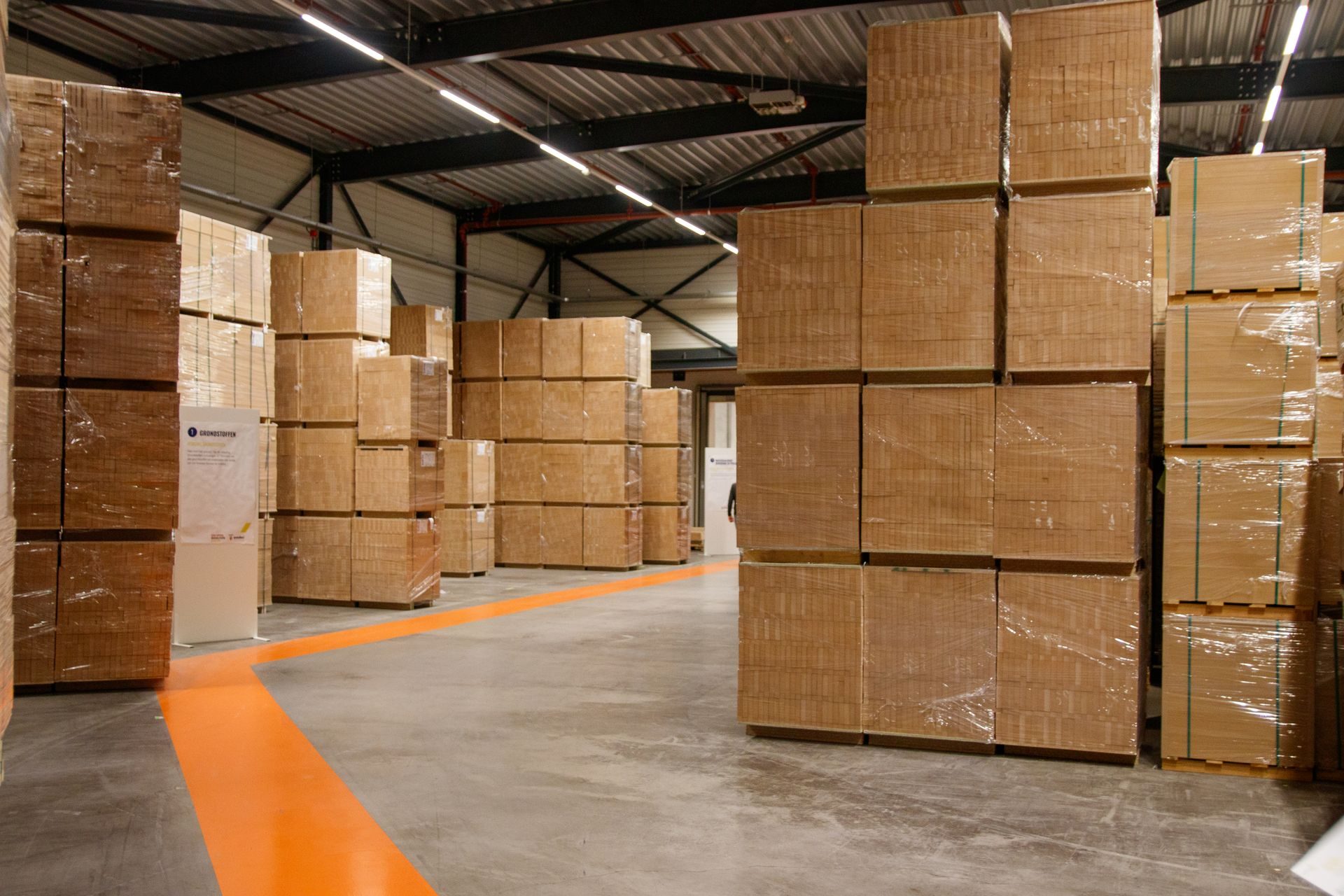 Film-wrapped pallets of corrugated cases stacked in a warehouse aisle
